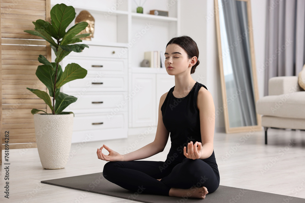 Beautiful girl meditating on yoga mat at home Beautiful girl meditating on yoga mat at home