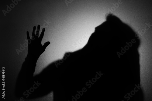 Silhouette of ghost behind glass against dark background © New Africa