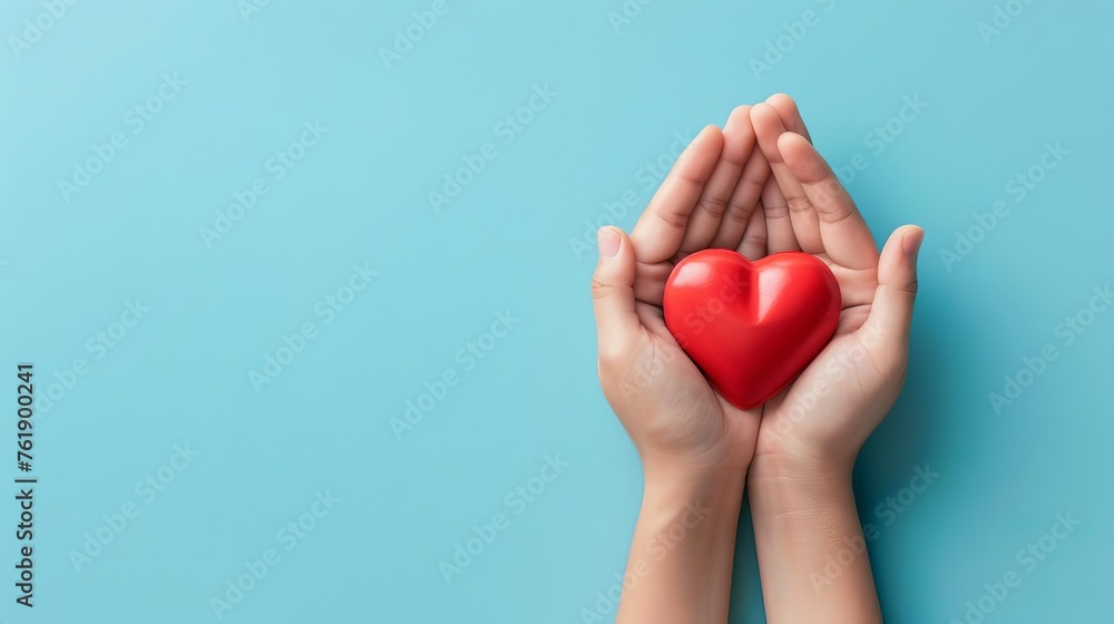 Fototapeta premium Hands Holding Red Heart on Blue Background, Love and Compassion Concept