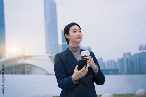 Confident Businesswoman with Coffee in Urban Setting © 昊 周