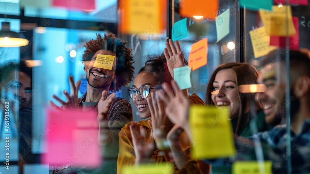 Obraz premium View through the glass of a group of businessmen Cheer each other to win ideas. While brainstorming with sticky notes on a glass wall in a modern office Contrast the emphasis on the notes on the wall.