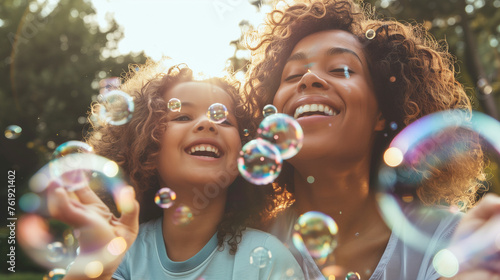 Mother and daughter enjoying blowing bubbles together, happy family moments.