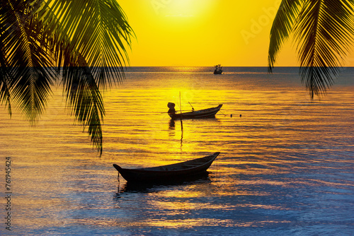 Sunset on tropical island sea beach, ocean sunrise landscape, palm tree leaves silhouette, fisherman boats, ships, yellow sky, golden sun reflection, blue water waves, summer holiday, vacation, travel © Vera NewSib