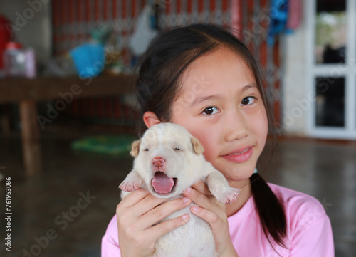 Asian young girl child showing Newborn puppies. Focus at a puppy in his hands.