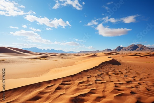 Erg landscape with sand dunes, mountains, and clear blue sky