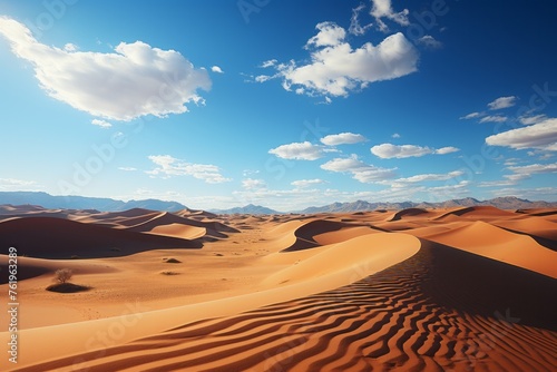 A natural landscape with sand dunes, mountains, and cumulus clouds in the sky