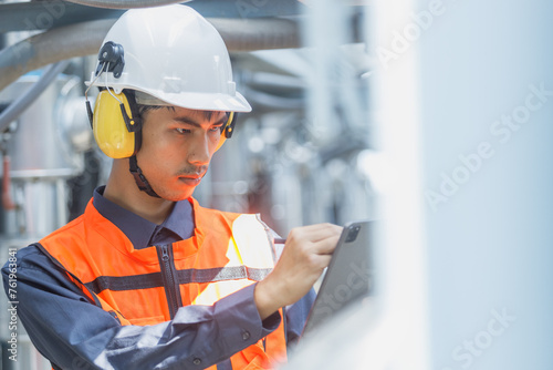 Male operator worker using tablet checking write record quality cooling air piping HVAC system at industrial building. Man engineer working on Heating Ventilation and Air conditioning system.