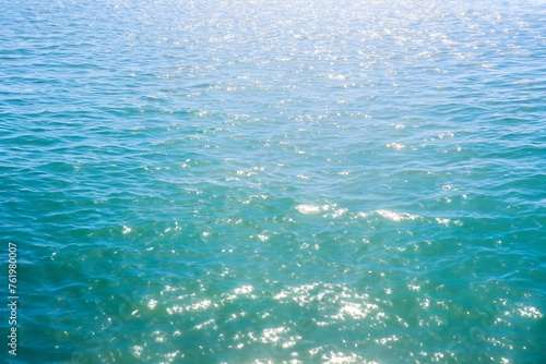 blue sea water background with sun reflection, closeup of photo.