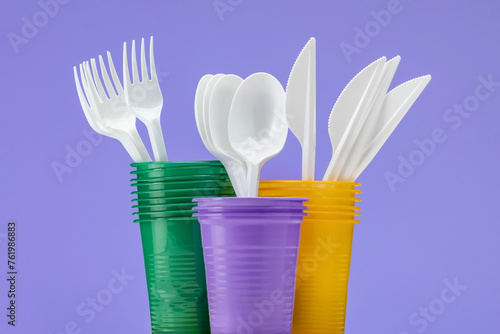 Set of multi-colored plastic cups with cutlery. Close-up, isolated.