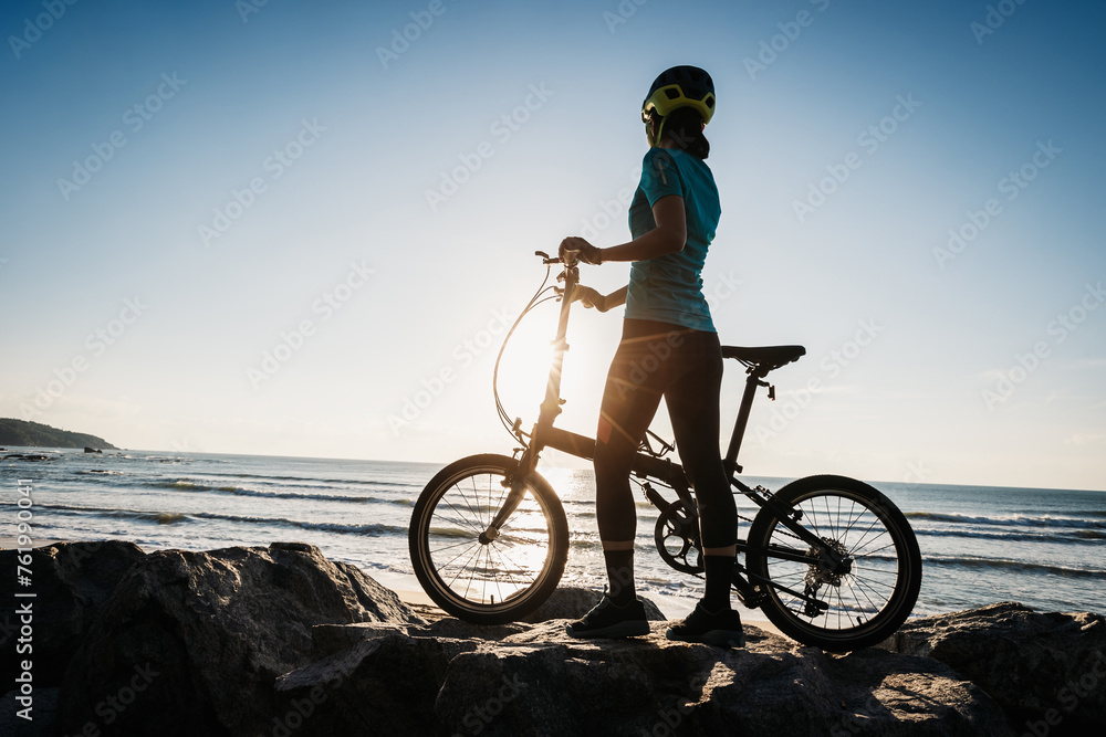 Woman taking a folding bike on sunrise seaside Woman taking a folding bike on sunrise seaside