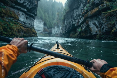 A person wearing a yellow kayak navigates down a river, paddling through calm waters © Ilia Nesolenyi