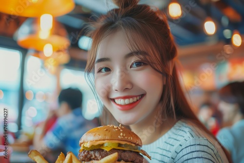 Young Asian Woman Smiling with a Burger at a Trendy Restaurant with Warm Ambient Lights