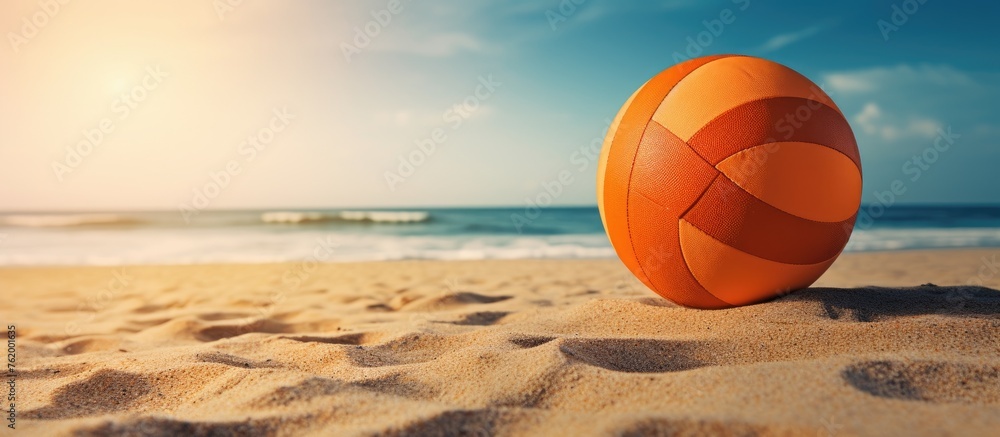 Orange volleyball ball on sandy beach