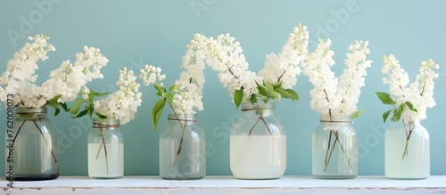 Five glass vases holding various blossoms arranged on a shelf