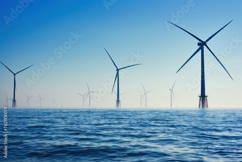 Offshore wind farm with multiple turbines rising from the sea against a clear blue sky in the daytime.