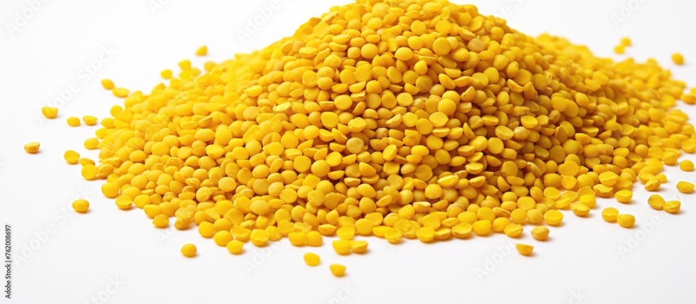 A close up of a pile of yellow lentonils on a white surface A close up of a pile of yellow lentonils on a white surface