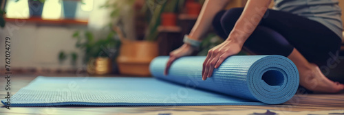 Close up of a woman's hands unrolling a yoga mat on the floor at home,  photo