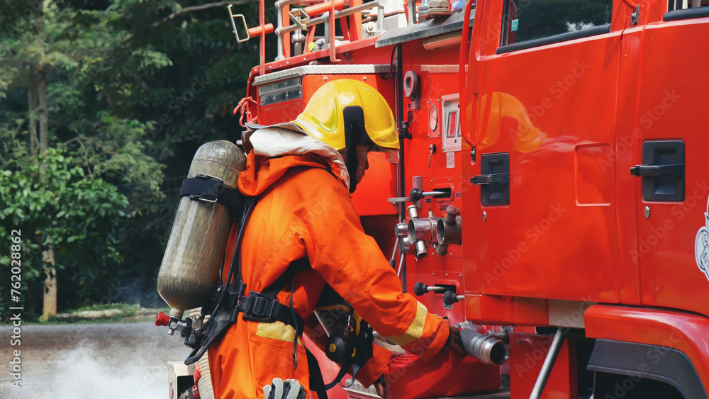 Fireman prepare equipment fighting extinguisher at fire engine truck. Firefighter fighting with smoke flame using fire hose, tube, chemical water foam spray at truck. Fireman wear hard hat protection