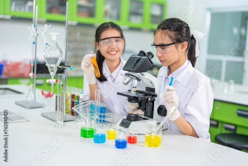 Two female scientists, a student, use a microscope to research a vaccine. On the table are beakers, experimental equipment, holding solution tubes. In the hospital lab Used for medicine