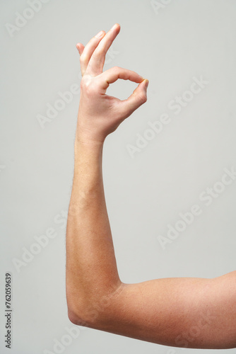 Male hand showing OK sign against gray background