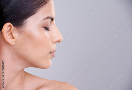 Woman, relax and profile with face in cosmetics, facial treatment or skincare on a gray studio background. Young female person, brunette or calm model in satisfaction for beauty or makeup on mockup