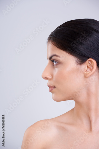 Woman, face and profile with skincare, cosmetics or facial treatment on a gray studio background. Young female person, brunette or model with smile in satisfaction for beauty, makeup or spa on mockup