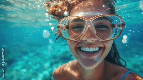 A woman is smiling while wearing goggles and swimming in the ocean. Concept of joy and excitement as the woman enjoys her time in the water © Woraphon