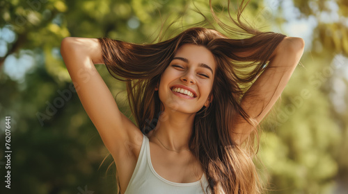 A young woman happily manages her long hair in the fresh outdoor air, expressing joy