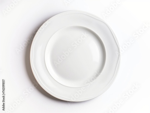 Top view of a clean white plate on a seamless white surface symbolizing simplicity and elegance.