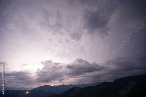 Evening thunderstorm with lightning in the mountains. Dramatic clouds during a thunderstorm pierce the light of lightning in a mountainous area. © Niko_Dali