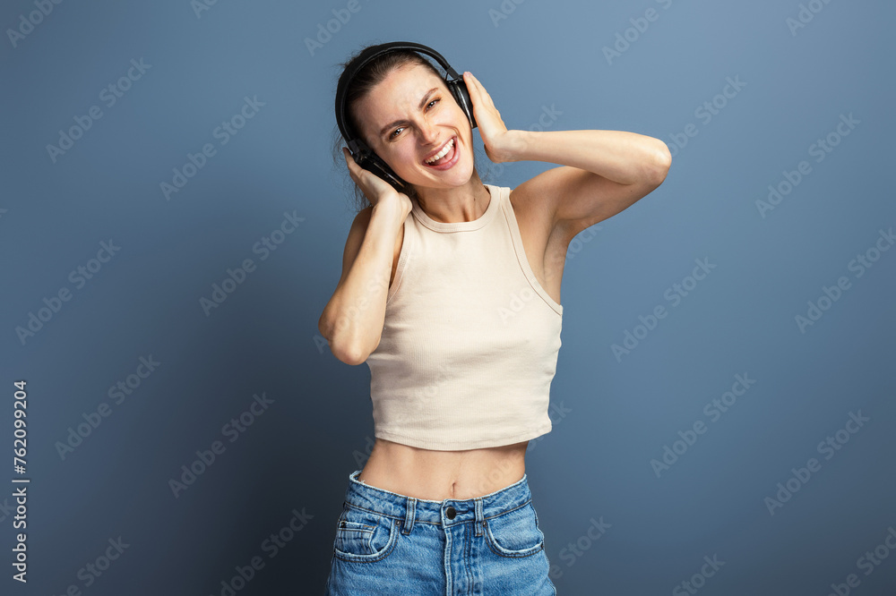 Young cheerful woman enjoying music with headphone, wearing casual top, isolated on grey studio background Young cheerful woman enjoying music with headphone, wearing casual top, isolated on grey studio background