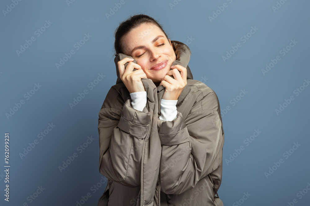 Young cheerful attractive woman wearing a grey coat during autumn and winter, isolated on grey studio background