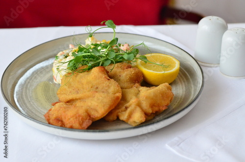 Photography Schnitzel with potatoes and herbs on a plate in a restaurant