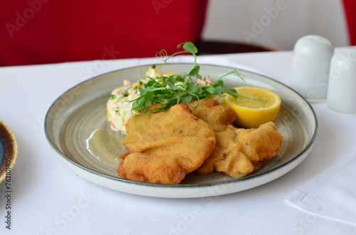 Wiener schnitzel with salad on a restaurant table.