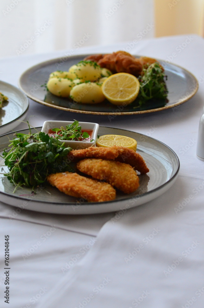 Schnitzel with potatoes and herbs on a plate in a restaurant Schnitzel with potatoes and herbs on a plate in a restaurant