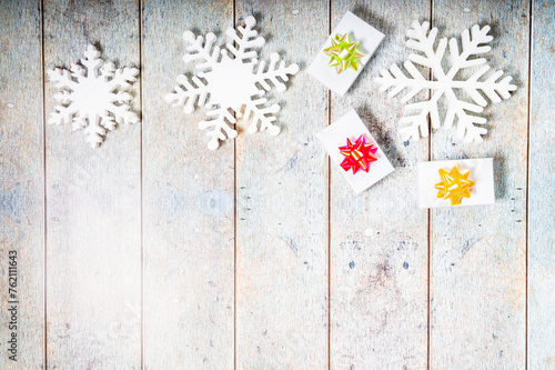 Snowflakes and a present with blue ribbon on a wooden background. Christmas winter flatlay with copyspace
