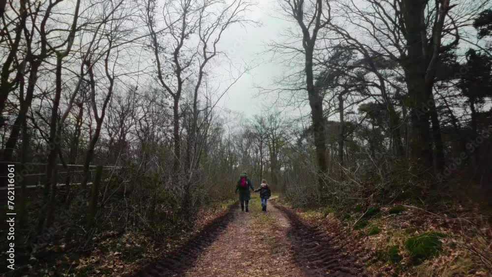 Mother and daughter walking on path in forest with muddy tracktor traces slowmotion Mother and daughter walking on path in forest with muddy tracktor traces slowmotion