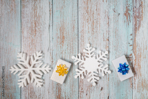 Snowflakes and presents on a light wooden background. Christmas winter flatlay with copyspace 