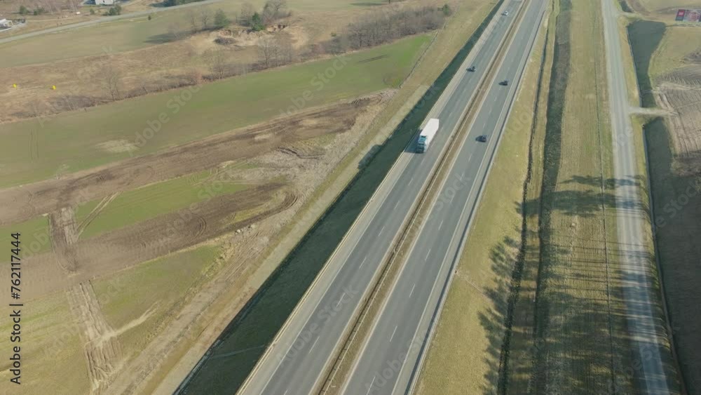Cars And Truck Driving Through The Highway Along The Countryside Road In Summer. - aerial shot Cars And Truck Driving Through The Highway Along The Countryside Road In Summer. - aerial shot