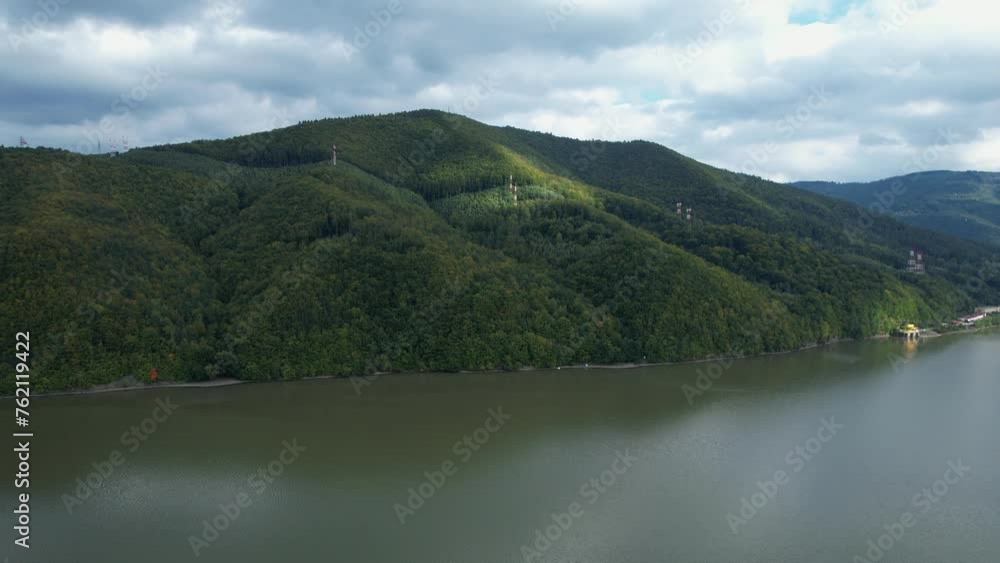 Overhead shot of Międzybrodzkie Lake with forested hills and homes, under moody clouds in Beskidy, Poland. Overhead shot of Międzybrodzkie Lake with forested hills and homes, under moody clouds in Beskidy, Poland.
