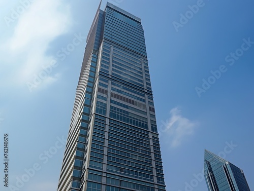 A tall skyscraper towers into the blue sky, showcasing modern architecture and urban development