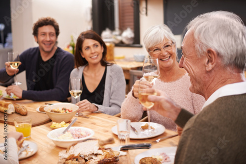Happy, cheers and family at supper in dining room for party, celebration or event at modern home. Smile, bonding and people enjoying meal, dinner or lunch together with wine for toast at house.