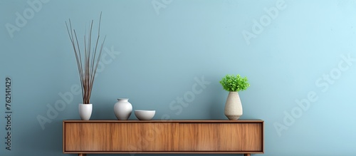 A wooden dresser with plantfilled vases and flowerpots on top, set against a blue wall. This stylish interior design features a mix of wood, plants, and decorative elements in a rectangular shape