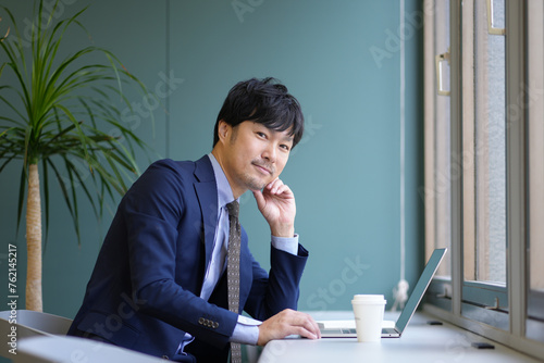 グリーンのオフィスとスーツとPCの男性
