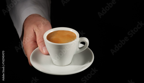 Waiter hand with coffee cup on black background