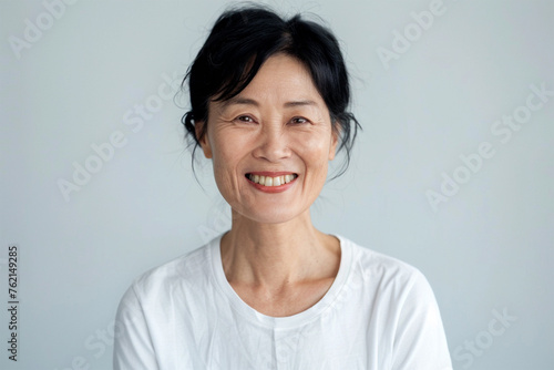 짧은 머리에 흰 티셔츠를 입고 미소 짓는 50대 한국인 여성 photo