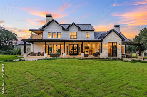 A beautiful two story modern farmhouse home with white paint and black trim, large open concept living room with a dark blue grey metal roof,