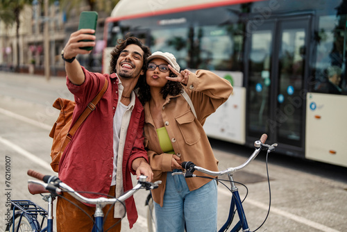 A happy couple is standing on street with bikes and taking selfies. © dusanpetkovic1