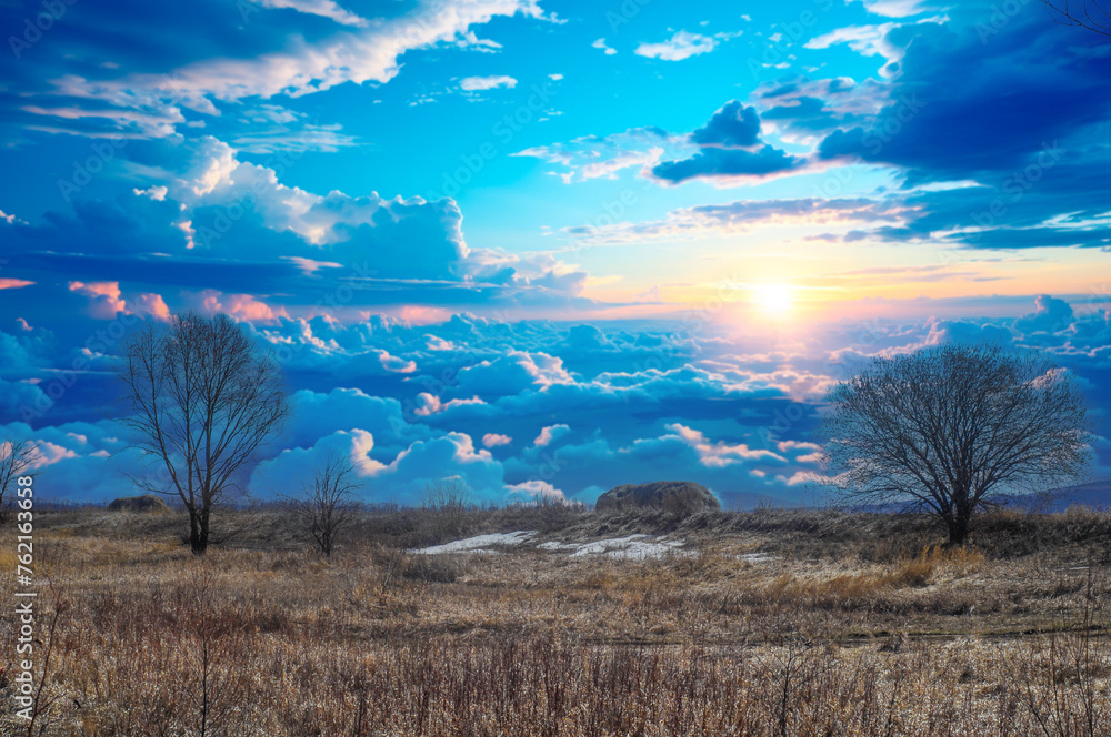 Yellow fields with sparse grass signal the beginning of spring. The trees are bare, without leaves. Getting ready for new growth. The last remnants of snow cling to the ground before melting.