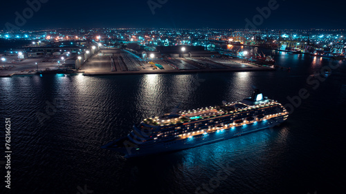 luxury cruise ship for first class passenger is sailing out of the port, motion effect low shutter speed to want movement of the cruise ship, night scene shipping port, container warehouse 